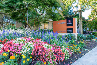 Exterior view of Marquis Mt. Tabor sign surrounded by vibrant flowers and landscaping.