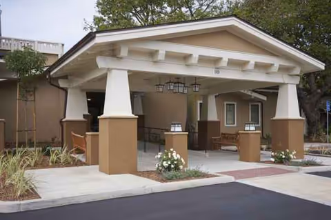 Covered porte-cochere entry with white columns and landscaping at Valle Verde senior living.