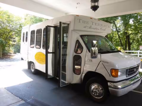 A white shuttle bus is parked at the building entrance under a covered driveway.