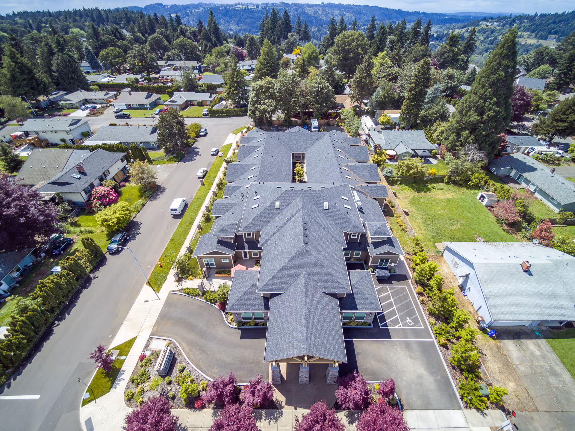 Aerial view of River Terrace Memory Care and the surrounding residential neighborhood with trees, parking spaces, and streets.