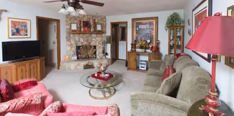 Cozy living room with beige furniture, stone fireplace, and glass coffee table.