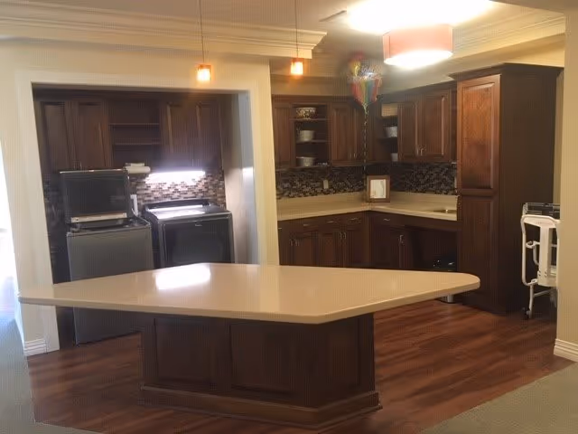 Kitchen with a large central island, dark wood cabinets, mosaic backsplash, pendant lights and a washer/dryer visible on the left.
