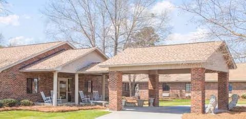 Pembroke Center entrance with brick columns, a covered drop-off, and outdoor seating.
