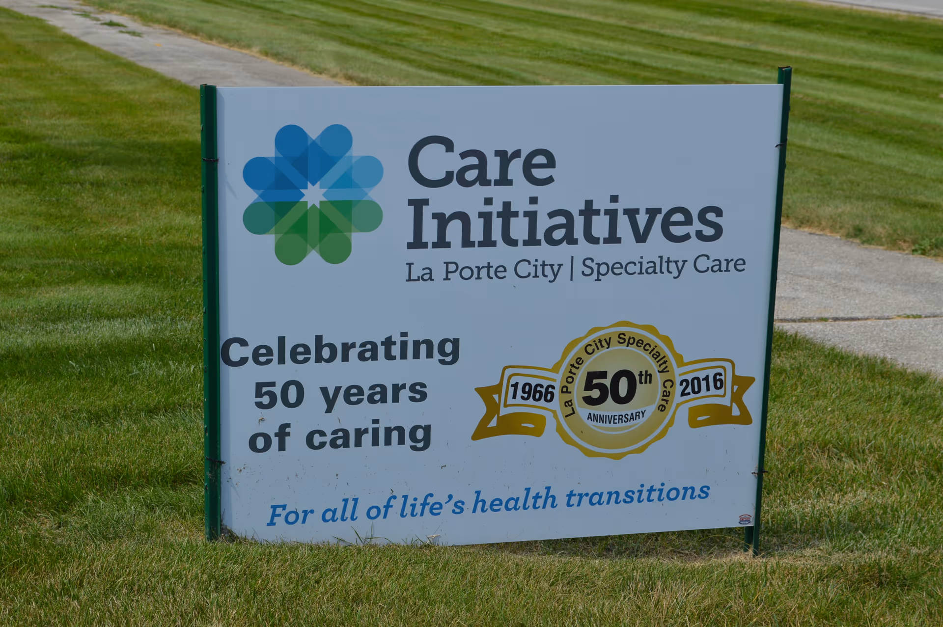 A lawn sign for Care Initiatives La Porte City Specialty Care celebrating 50 years of caring from 1966 to 2016, with the tagline 'For all of life's health transitions'.
