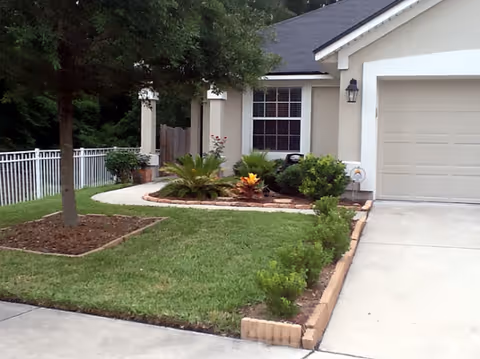 Front yard and entrance of a beige, residential-style senior facility with landscaping.