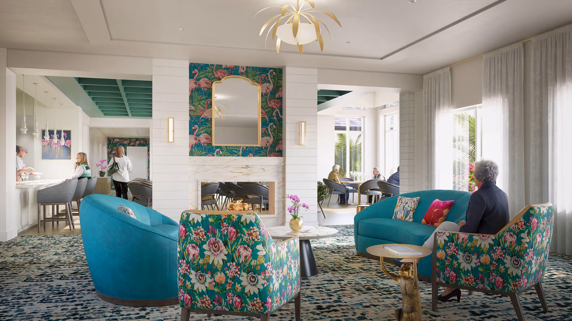 Bright senior living lounge with teal and floral upholstered chairs and sofas arranged around a coffee table facing a fireplace, with people seated and a dining area visible beyond.