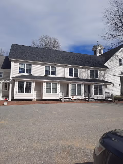 Canterbury Hall exterior: white two-story senior living building with large windows and entry steps.