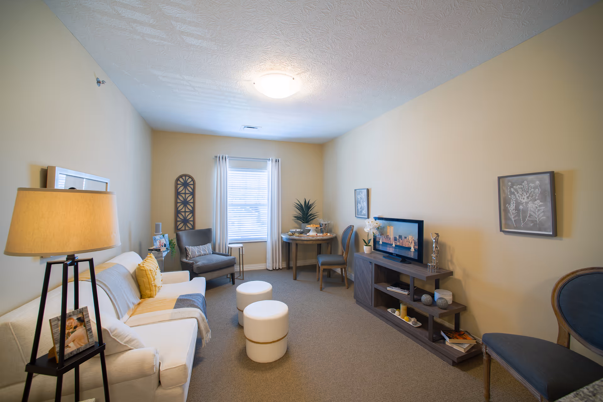 Cozy living room in a senior facility with sofa, chairs, TV, and decor.