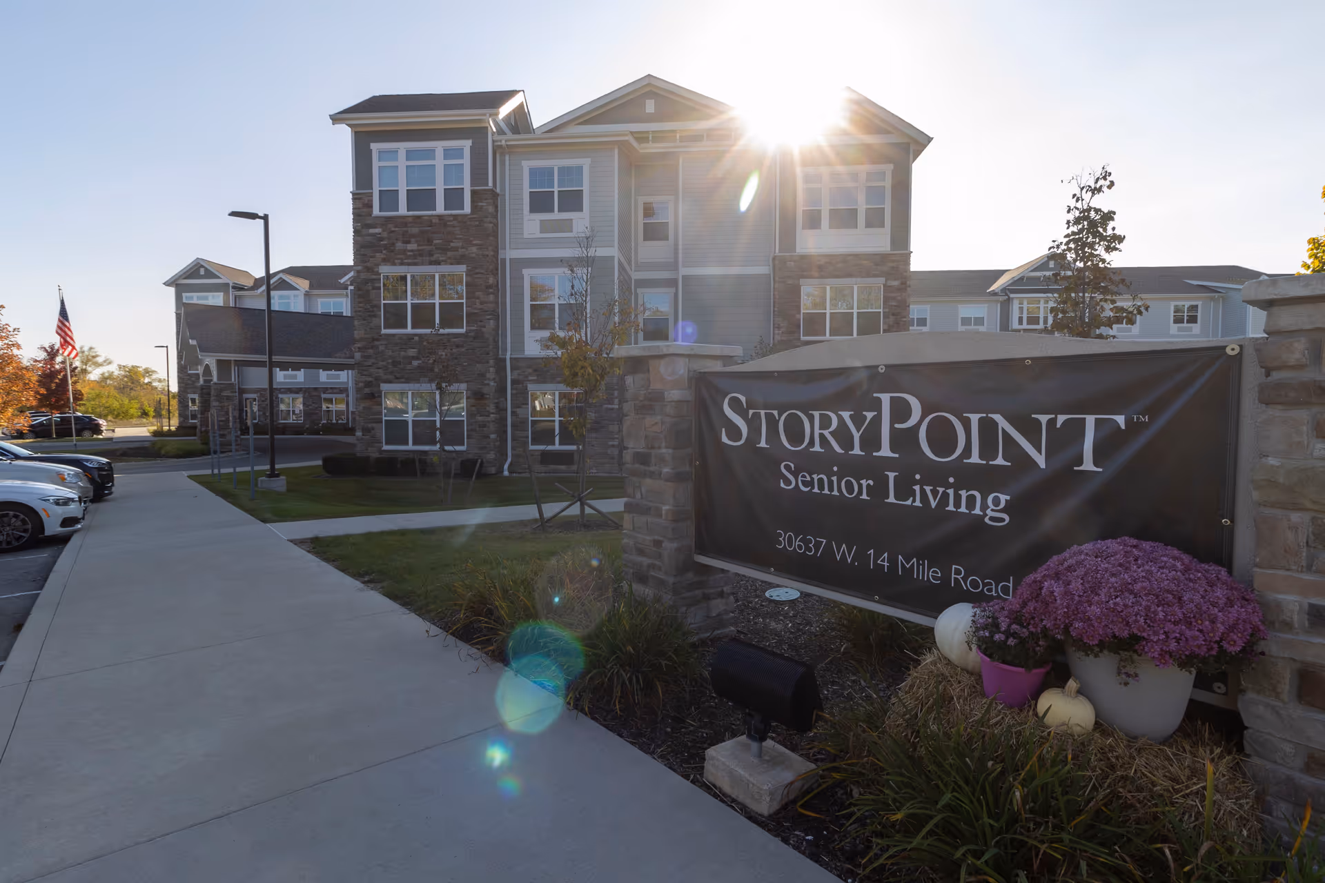 Front exterior of the StoryPoint Senior Living building and entrance with a sidewalk, parked cars, and a large sign in the foreground.