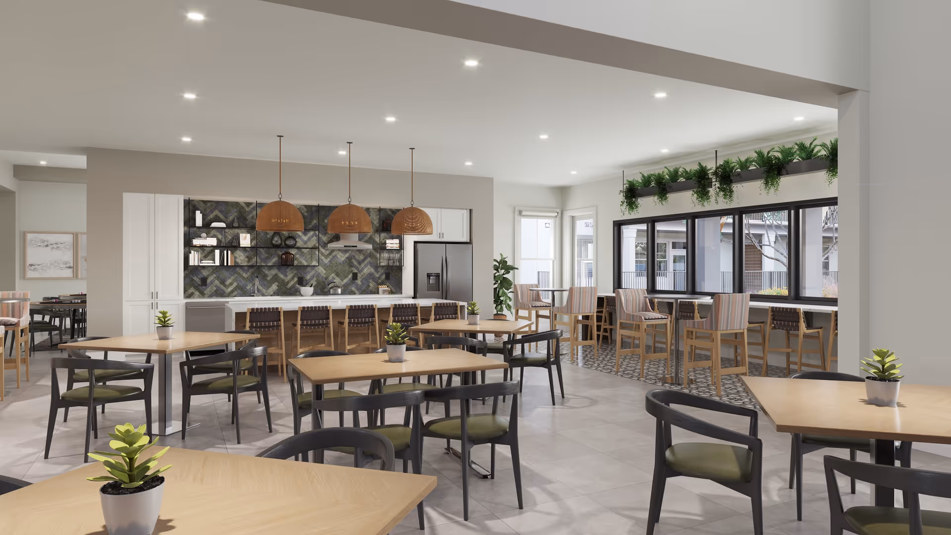 Bright communal dining area with multiple tables and chairs, a modern kitchenette with pendant lights, and large windows with bar seating.