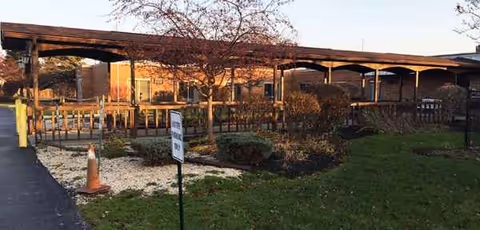 Carington Park outdoor courtyard with a covered walkway, manicured shrubs, and a sign.