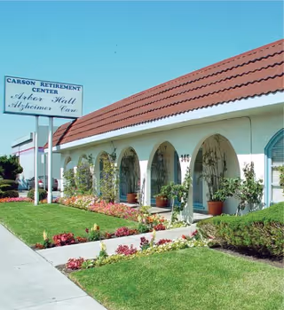 Exterior view of Carson Retirement Center with arches, potted plants, and a manicured lawn.