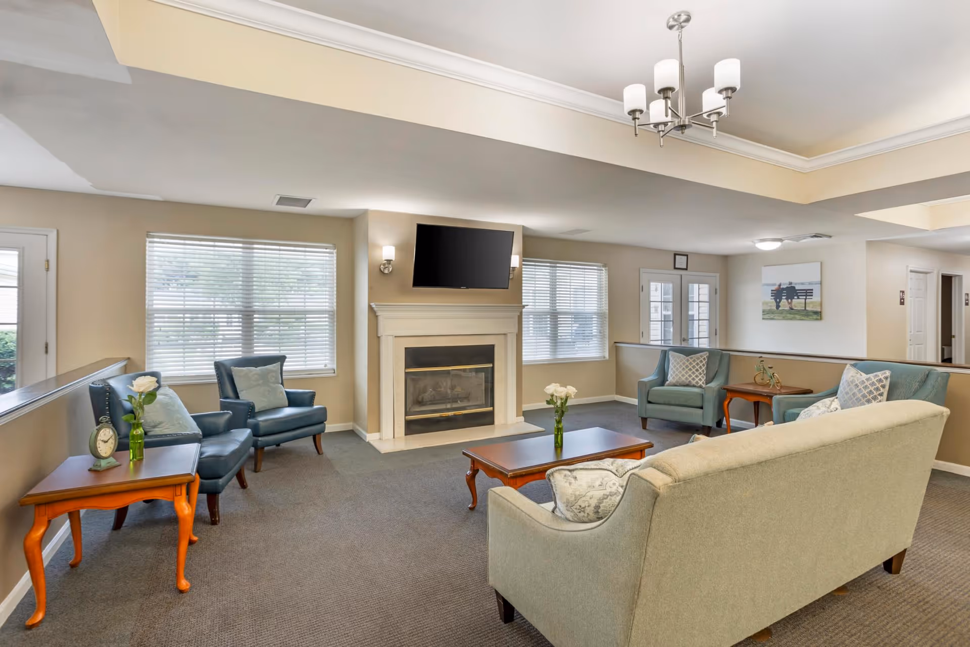 Communal living room with sofas and armchairs arranged around a fireplace and wall-mounted TV.