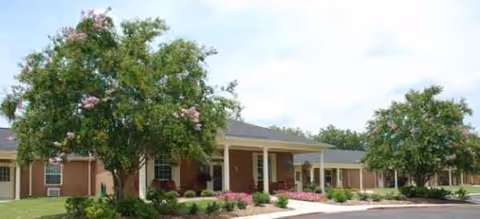 Single-story senior living facility with a covered entrance, landscaping, and a parking area.