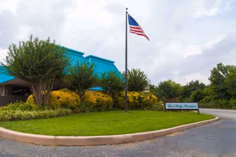 East Ridge Residence exterior with landscaped front yard, flagpole, and building sign.