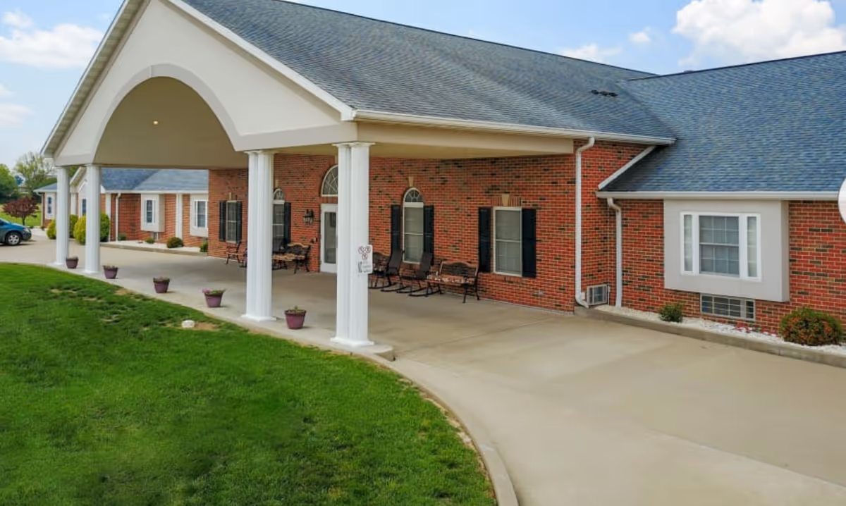 Brick senior living facility exterior with a covered entrance and white columns.