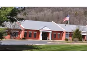 Front view of Highland Manor, a brick senior living facility with an American flag.