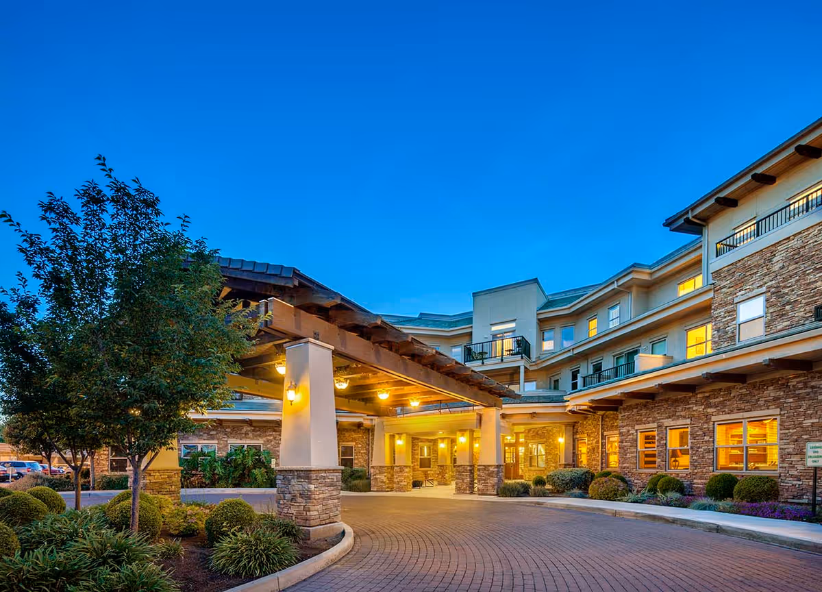 Exterior view of Covenant Living of Turlock, showing entrance canopy and lit windows at dusk.