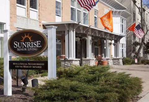 Sunrise Senior Living facility exterior with signage, flags, and landscaped entrance.