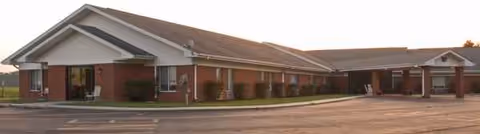 Single-story brick senior living facility with a long front entrance and parking area.
