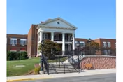 Front exterior of Pleasant Ridge Manor with steps, columns, and landscaped entrance