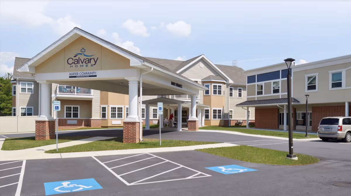 Covered entrance and drop-off of the Calvary Homes senior living building with handicap parking spaces in the foreground.