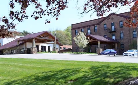 Exterior view of Northland Lodge Assisted Living with entrance canopies, parking, and lawn.