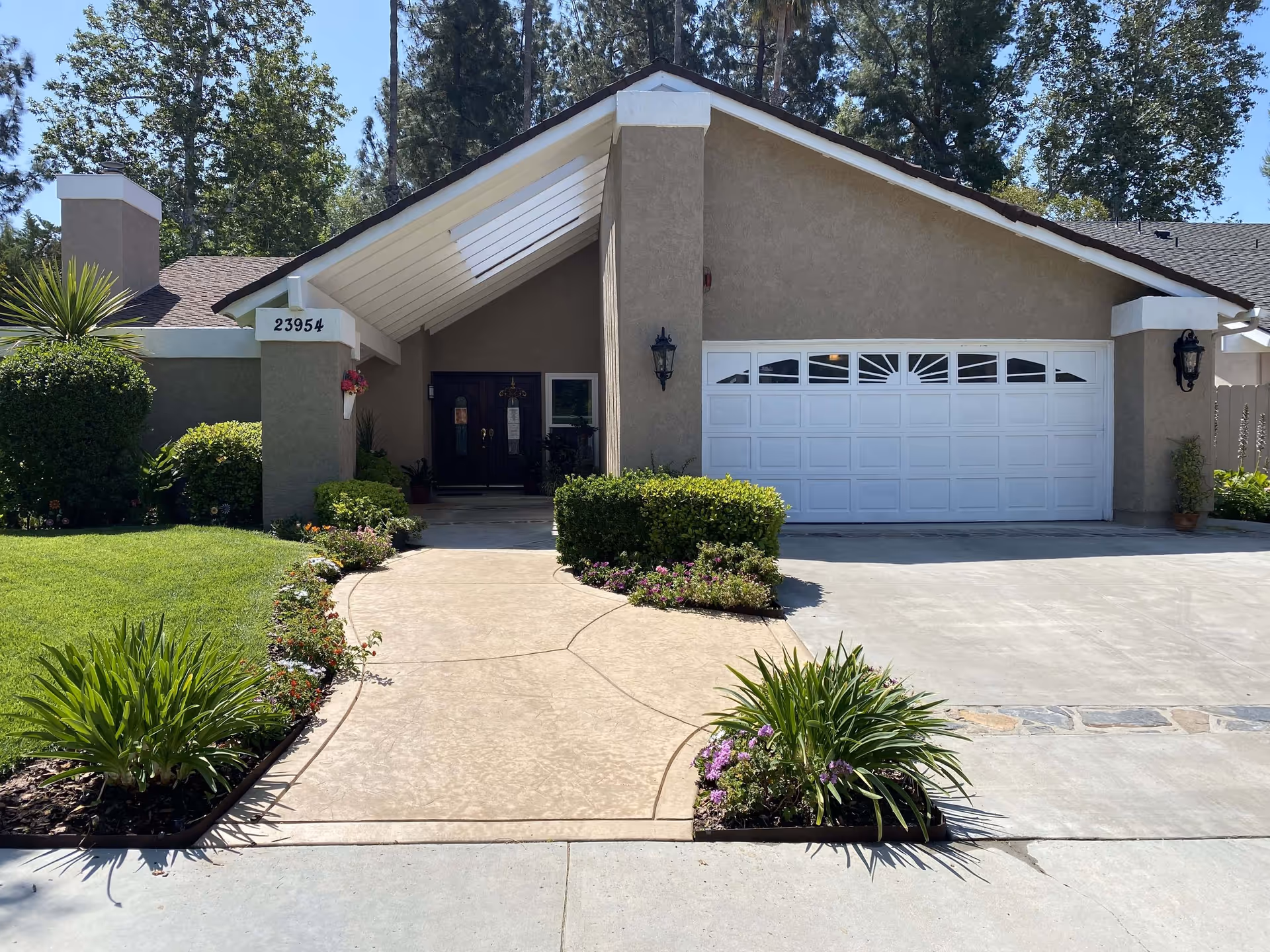 Front exterior of a single-story house with a driveway, attached garage, and landscaped walkway to the front door.