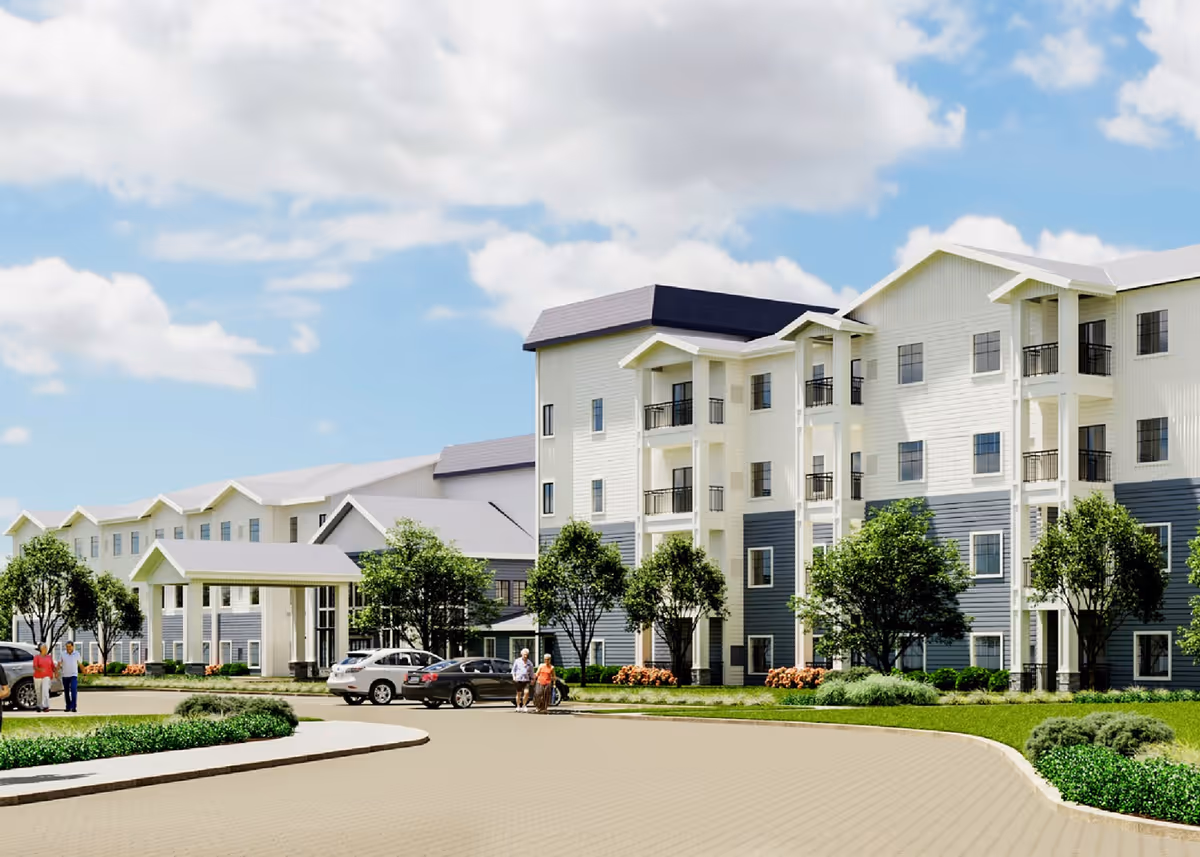Exterior view of a modern multi-story senior living facility with white and gray siding, balconies, trees, and parked cars under a partly cloudy sky. Several people are walking near the entrance.