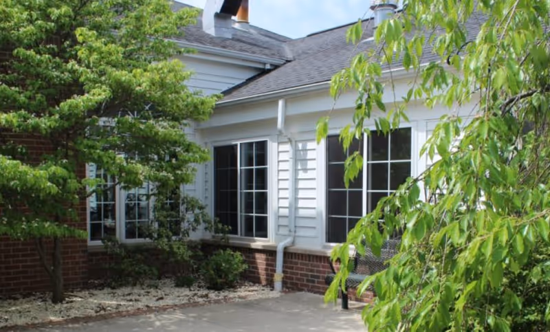 Exterior view of Crystal Creek Assisted Living and Memory Care building with windows and surrounding trees.