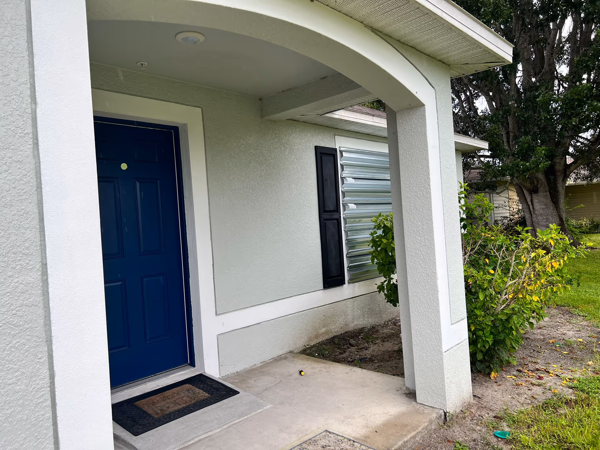 Exterior view of the entrance to a senior living facility with a blue door and plants nearby.