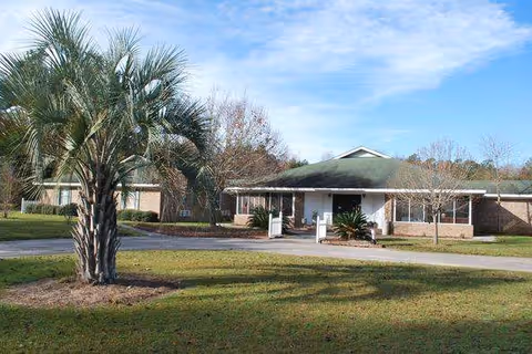 Single-story senior living facility with front entrance, palm tree, and manicured lawn.