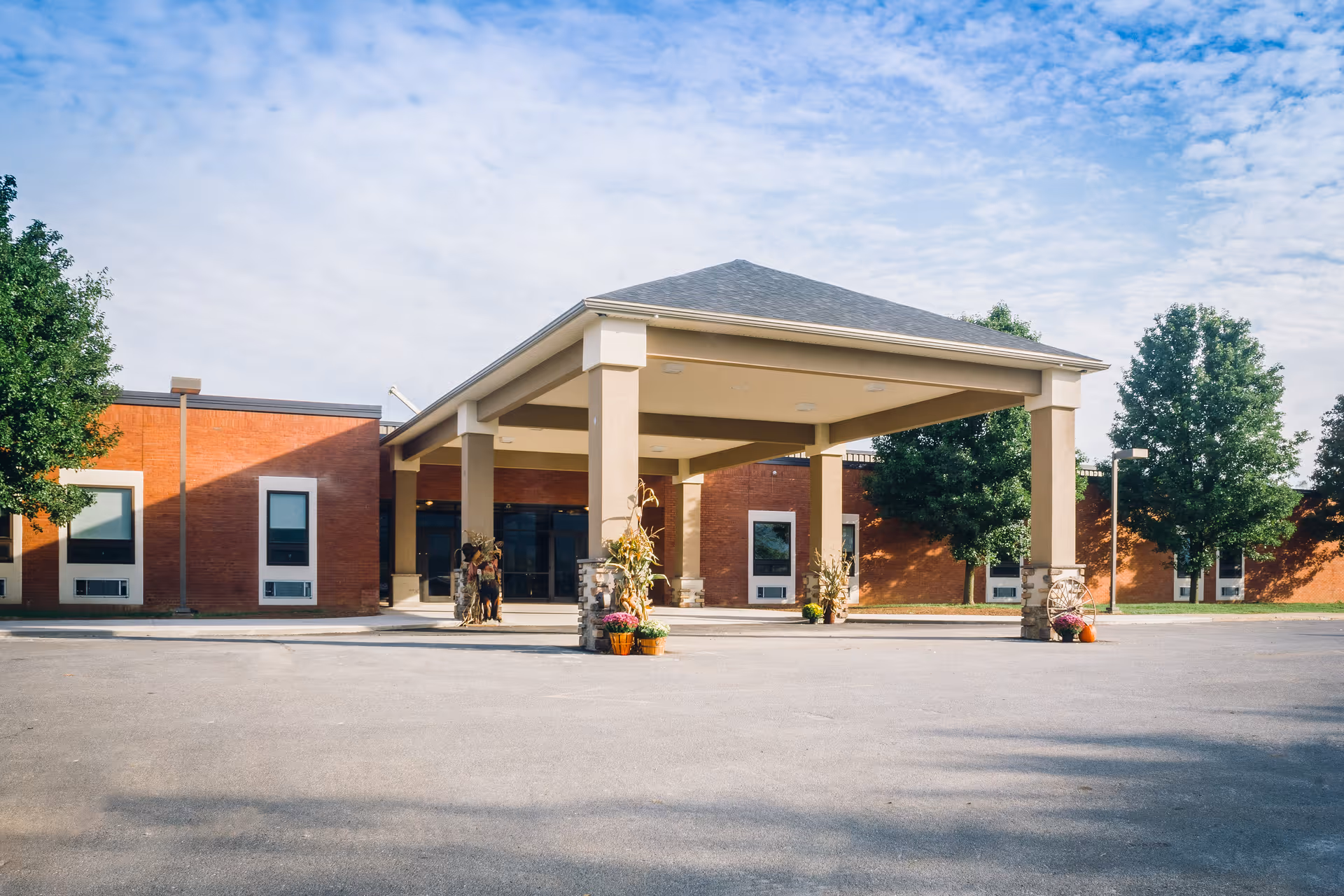 Front entrance of a single-story brick senior living facility with a covered porte-cochere and seasonal decorations.