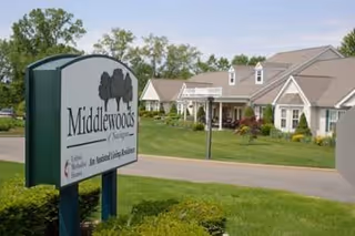 Exterior view of Middlewoods of Newington facility with front sign and landscaping.