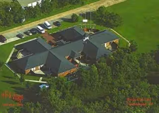 Aerial view of Independence Village facility, showing multiple connected buildings, parking lot, and trees.