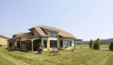 Exterior view of Camphill Ghent building with manicured lawn and outdoor seating.