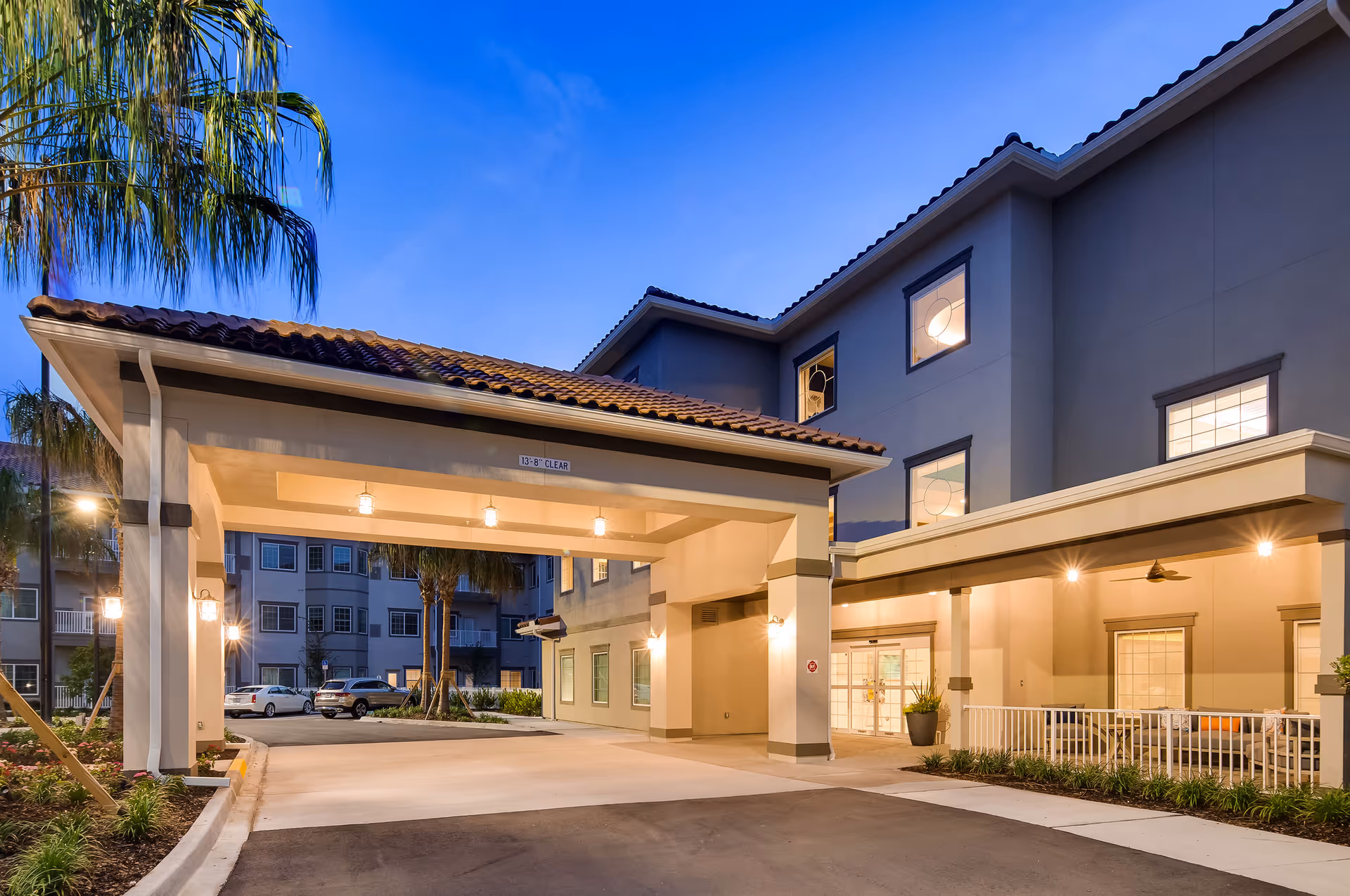 Front entrance and porte-cochère of Windsor Pointe of Jacksonville at dusk with lit exterior and parked cars visible.