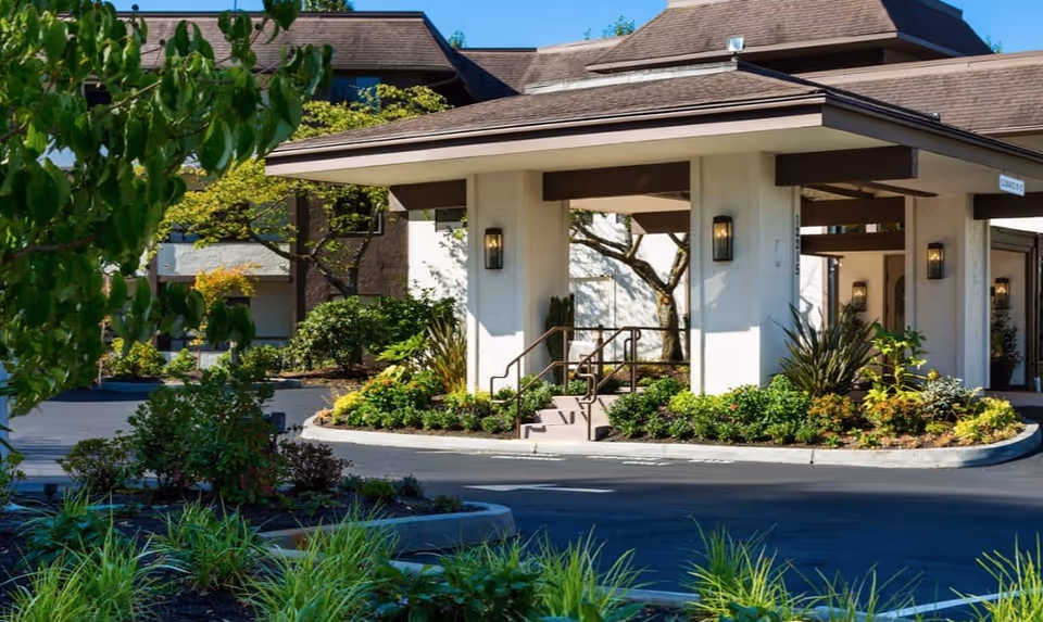 Exterior view of Madison House Assisted Living entrance with landscaping and a covered walkway.