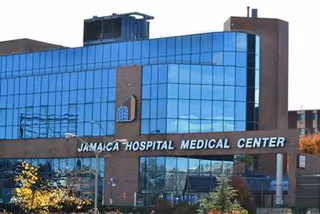 Exterior view of Jamaica Hospital Medical Center building with blue glass facade and sign.