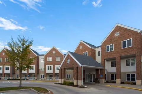 Brick senior living building with a covered entry and blue sky.