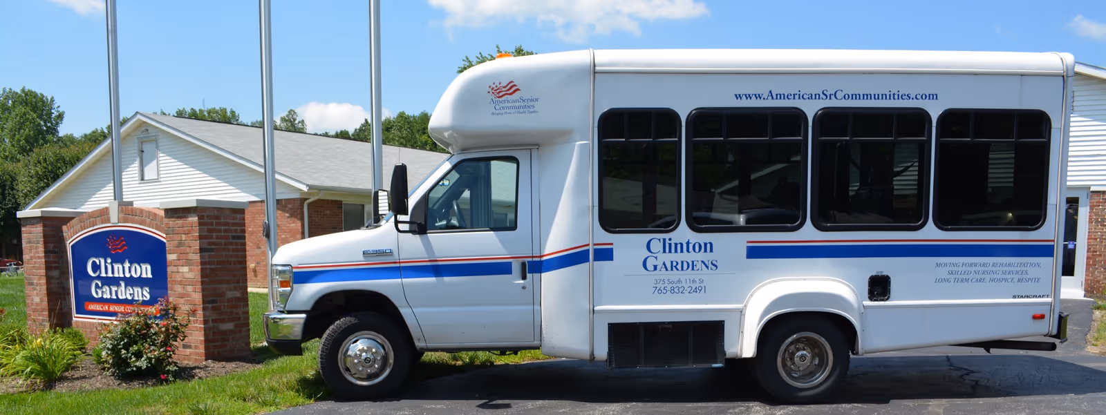 A Clinton Gardens shuttle bus parked in front of the facility beside a brick sign reading Clinton Gardens.