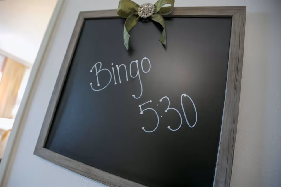 A framed chalkboard hanging on a wall reads "Bingo 5:30" with a decorative ribbon at the top.