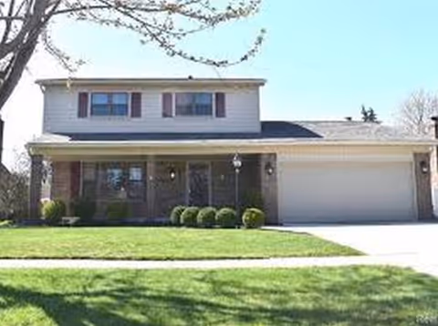 Front view of a two-story residence with a garage, manicured lawn, and walkway.