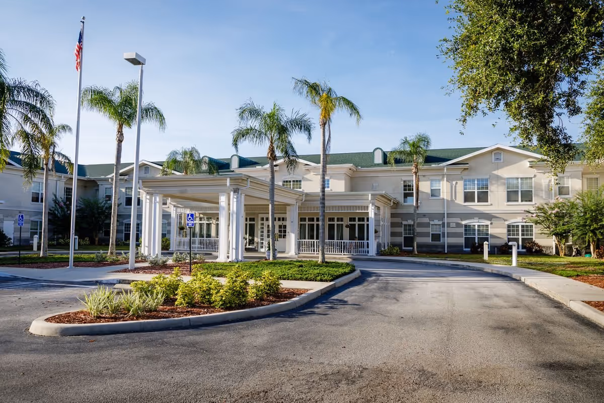 Front exterior view of Sodalis Stuart facility with a covered entrance, palm trees, an American flag, and a clear blue sky.