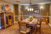 Formal dining room with a wooden table set for six, upholstered chairs, sideboard, chandelier, and warm neutral decor.