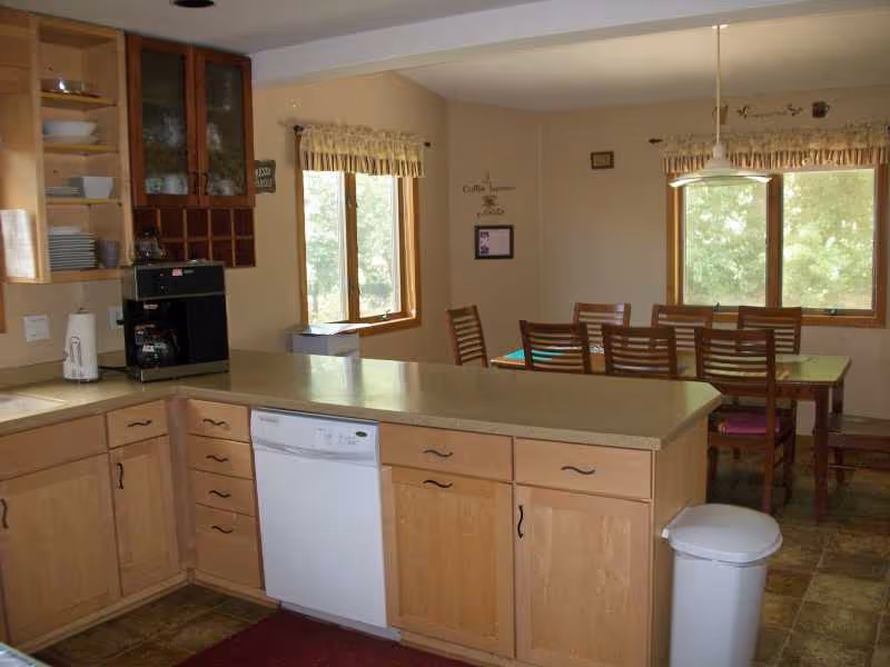 A homey kitchen with wood cabinets, a long counter, and a dining table.