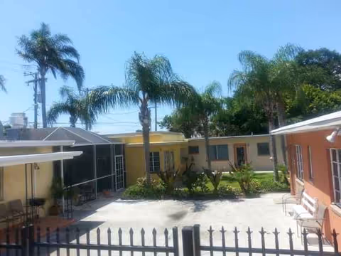 Sunny outdoor courtyard at HB Anderson Home ALF with palm trees and seating.