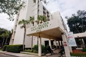 Front entrance of the Mary Walker Apartments building showing a covered porte-cochère, palm trees, and a freestanding sign.