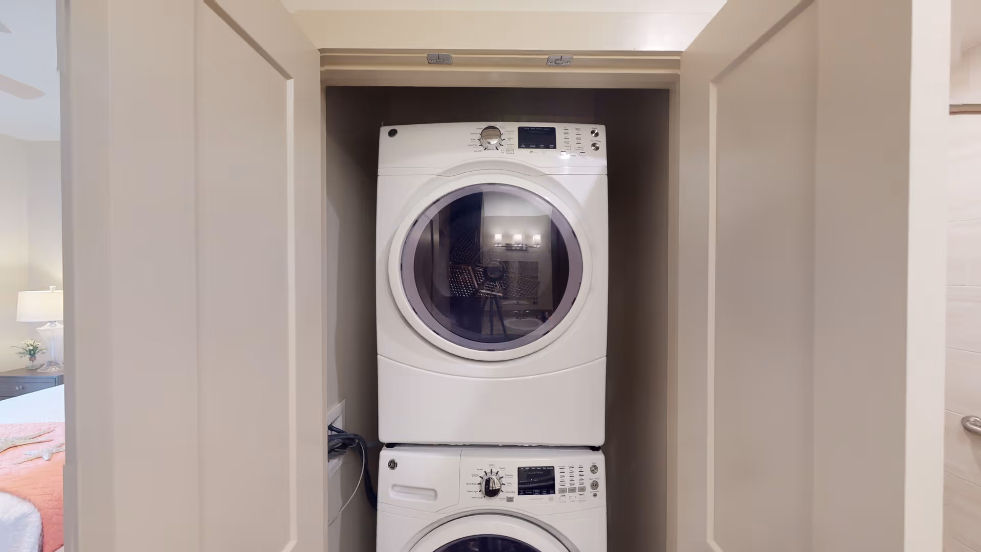 A stacked white washer and dryer in a small closet with open doors.