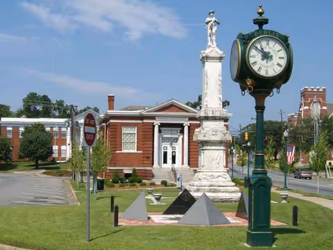 Exterior view of The Villas at Bellevue with a clock statue and manicured lawn.